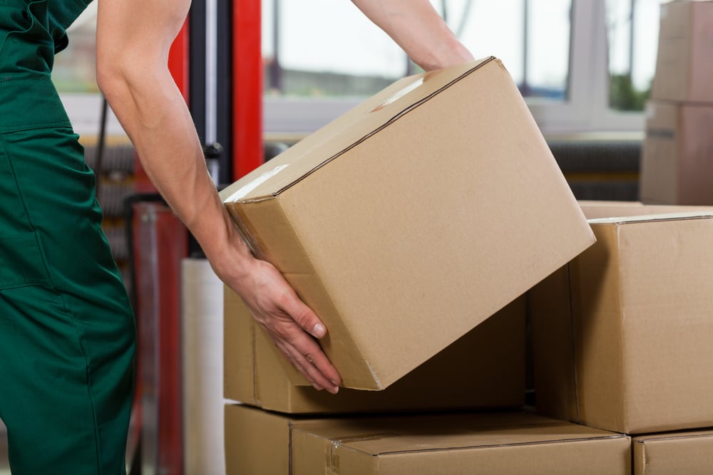 A_Hands of warehouse worker lifting box, horizontal